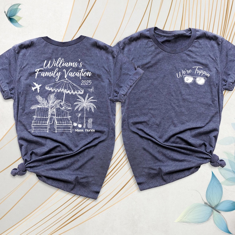 Pode incluir: Duas camisetas azul marinho. Uma apresenta "Williams's Family Vacation 2025 Miami, Florida" com gr&aacute;ficos de praia. A outra tem "We're Trippin" e &oacute;culos de sol. Ambas t&ecirc;m mangas curtas e s&atilde;o amarradas na parte inferior. Para f&eacute;rias.