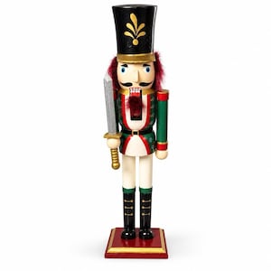 May include: A wooden nutcracker figurine wearing a tall black hat with gold leaf detail, a green and white uniform with red accents, and black boots. The figure holds a silver sword in its right hand and has dark red hair and a black moustache.