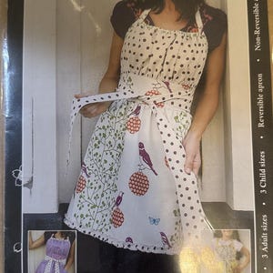 May include: A reversible apron sewing pattern with a polka dot and bird design. The apron features a white base with brown polka dots, and a lower section with a bird and botanical print. The text "The Pretty Ditty Apron" is visible.