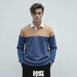 Op de afbeelding: Een shirt met lange mouwen en kleurblokken met een witte kraag, een bruin bovenstuk en een blauw onderstuk. Het shirt heeft een knoopsluiting met drie knopen en wordt gedragen met een zwarte broek. De merknaam "BANFF STONE" is zichtbaar.