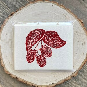 May include: A red and white greeting card with a red illustration of a raspberry branch with three raspberries.