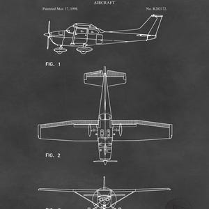May include: A black and white blueprint of an aircraft, with three views: side, top, and front. The text reads "UNITED STATES PATENT OFFICE" and "CESSNA AIRCRAFT COMPANY, OF WICHITA, KANSAS. AIRCRAFT". The patent date is March 17, 1998.