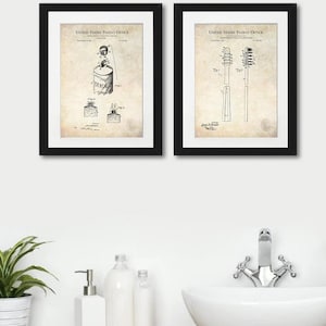 May include: Two framed vintage patent prints in black frames. The left print shows a drawing of a toothpaste tube with the text "United States Patent Office" and "Dental Soap". The right print shows a drawing of a toothbrush with the text "United States Patent Office".