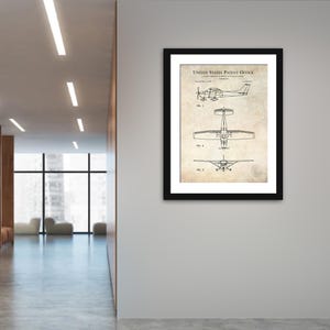 May include: A framed patent print of an aircraft, displayed on a white wall. The print, with the text "UNITED STATES PATENT OFFICE", features three diagrams of the aircraft from different angles. The frame is black, and the print has a vintage paper appearance.