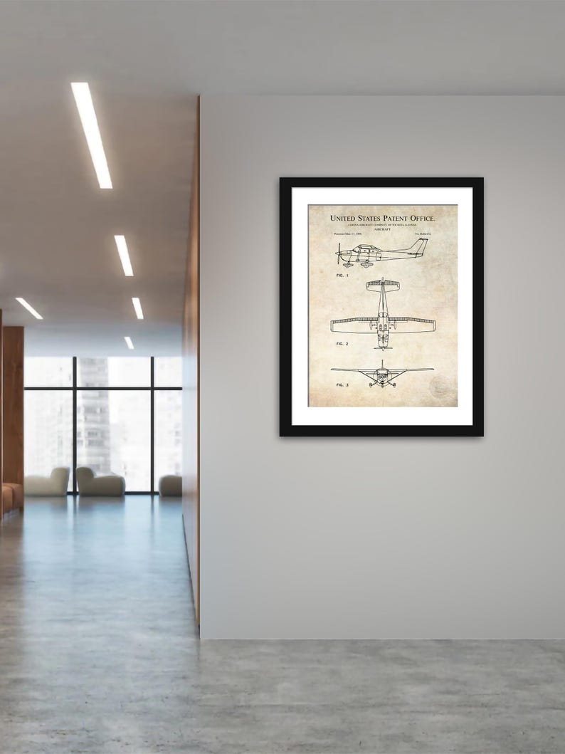 May include: A framed patent print of an aircraft, displayed on a white wall. The print, with the text "UNITED STATES PATENT OFFICE", features three diagrams of the aircraft from different angles. The frame is black, and the print has a vintage paper appearance.
