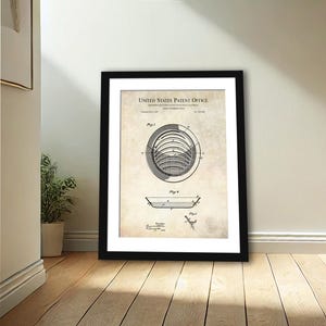 May include: A framed patent print showing a diagram of a golf putting aid. The black and white print is set against a beige background and includes the text "United States Patent Office". The frame is black.