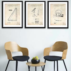 May include: Three framed vintage patent prints from the United States Patent Office. The prints are in black frames and feature technical drawings. Two wooden chairs with black seats and a small round table with a bowl of fruit are in front of a white wall.