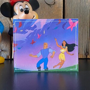 May include: A vintage trading card featuring a cartoon image of a man and a woman standing in a field with a purple sky and colorful feathers falling from the sky. The man is wearing a blue shirt and blue pants. The woman is wearing a yellow dress and has long black hair.