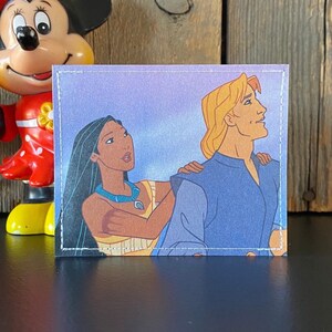 May include: A close-up of a cartoon image of Pocahontas and John Smith from the Disney movie Pocahontas. Pocahontas is wearing a brown and yellow dress and a turquoise necklace. John Smith is wearing a blue shirt. The background is a purple sky.