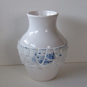 May include: White ceramic vase with a blue and white mosaic design around the middle.