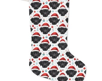 Könnte beinhalten: Ein Weihnachtsstrumpf mit einem sich wiederholenden Muster aus schwarzen Labradoren mit Weihnachtsmützen. Der Hintergrund ist weiß mit roten und blauen Weihnachtskugeln. Oben befindet sich eine weiße Schlaufe.