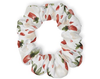 May include: White scrunchie with a watercolor strawberry pattern. The design features red strawberries, green leaves, and small red heart accents. The scrunchie is made of a soft fabric and is suitable for various hairstyles.