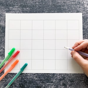May include: A white gridded paper with a pencil and five colored markers. The markers are yellow, green, red, orange, and teal.