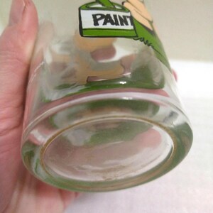Op de afbeelding: Een helder glazen drinkglas met een cartoonillustratie van een persoon die een verfpot houdt. De verfpot is gelabeld met "PAINT".
