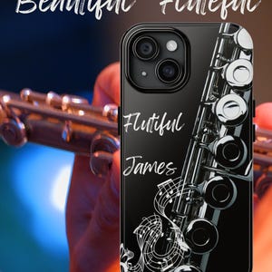 以下が含まれることがあります： 銀色のフルートのデザインと「Flutiful James」という白い文字が印刷された黒い携帯電話ケースです。