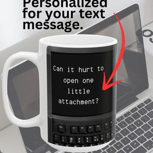 May include: White ceramic mug with a black and white image of a computer screen with the text "Can it hurt to open one little attachment?" printed on it. The mug has a black handle.