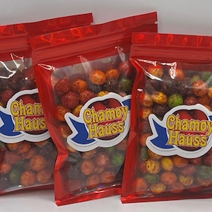 May include: Three red resealable bags filled with colorful candy coated peanuts. The bags have a blue and white label with the text "Chamoy Haus" printed on them.