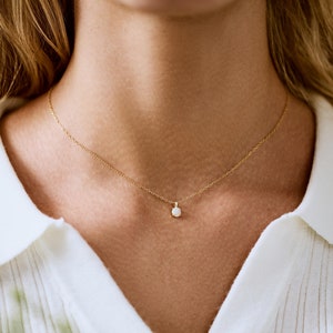 May include: A delicate gold chain necklace with a small, round opal pendant.