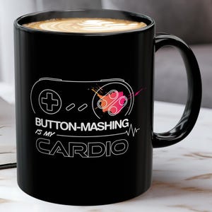 May include: Black coffee mug with a white outline of a video game controller and the text "BUTTON-MASHING IS MY CARDIO".