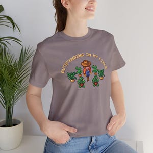 This is a Bella+Canvas 3001 Unisex Jersey Tee with the “Cozy Game Farm Life Shirt Outstanding In My Field Pixel Art for Farming Game Fans” design on the front of the shirt. Image 2