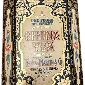 Può includere: Scatola di tè antica "China Tea" con motivi floreali e volute dorate su sfondo nero. Presenta il testo "China Tea" e "Thomas Martin & Co, Importers & Blenders, New York". Etichetta: "One Pound Net Weight", circa 454 grammi.