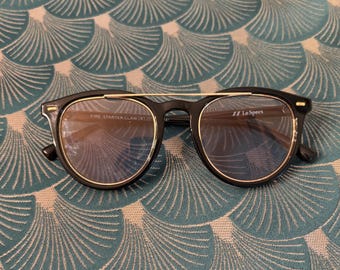 Occhiali da sole vintage Le Specs con montatura nera e lenti chiare.