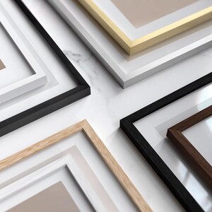 K&ouml;nnte beinhalten: Eine Auswahl gerahmter Kunstdrucke mit verschiedenen Rahmenstilen. Die Rahmen sind in Schwarz, Wei&szlig;, Gold und Naturholz gehalten. Die Drucke haben Passepartouts in neutralen Farbt&ouml;nen, was eine saubere, moderne &Auml;sthetik ergibt. Ideal f&uuml;r die Inneneinrichtung.