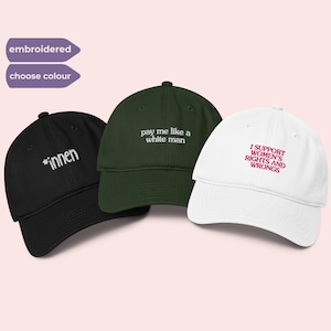 Op de afbeelding: Drie geborduurde baseballpetten in zwart, groen en wit. De zwarte pet heeft het woord "*innen", de groene pet zegt "pay me like a white man" en de witte pet zegt "I SUPPORT WOMEN'S RIGHTS AND WRONGS".
