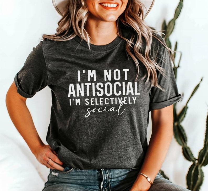 Op de afbeelding: Een donkergrijs T-shirt met de tekst "I'm not antisocial I'm selectively social" in wit gedrukt.