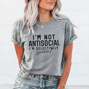 Op de afbeelding: Grijs T-shirt met de tekst "Ik ben niet antisociaal, ik ben selectief" in het zwart gedrukt.