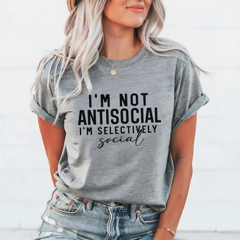Op de afbeelding: Grijs T-shirt met de tekst "Ik ben niet antisociaal, ik ben selectief" in het zwart gedrukt.