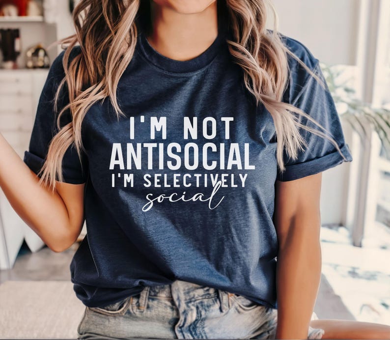 Op de afbeelding: Een marineblauw T-shirt met witte tekst die "Ik ben niet antisociaal, ik ben selectief sociaal" zegt.