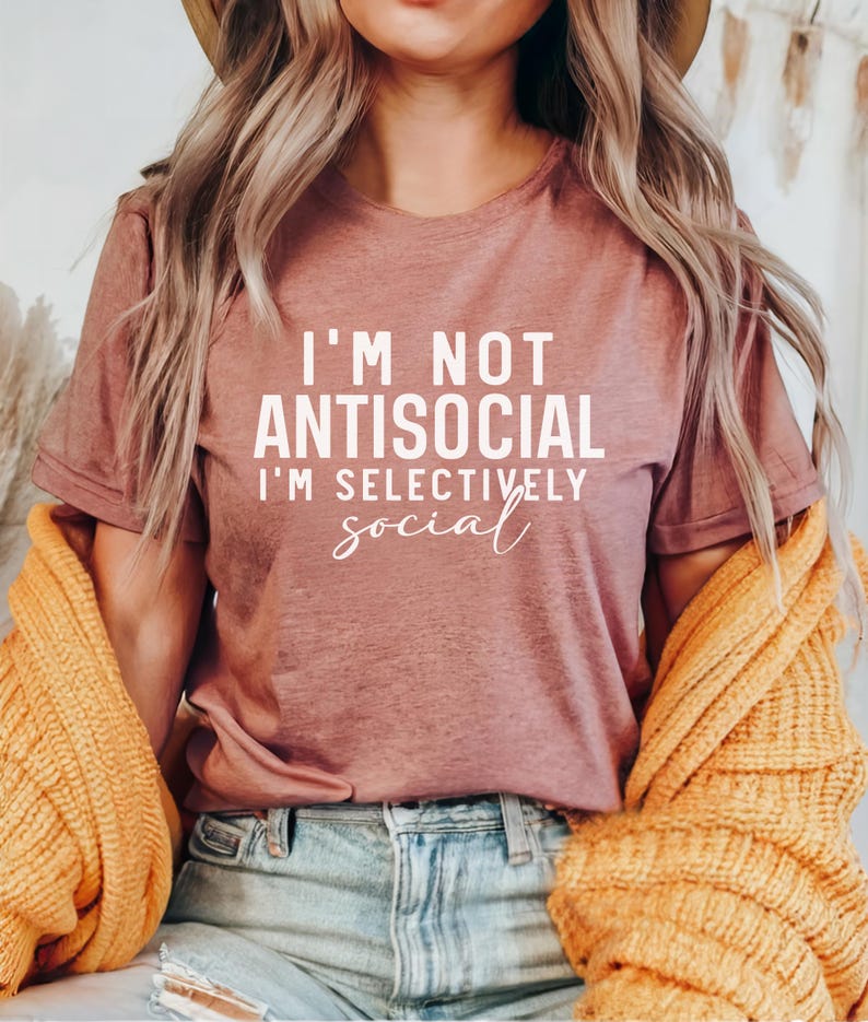 Op de afbeelding: Een mauve t-shirt met de tekst "I'm not antisocial I'm selectively social" in witte letters.