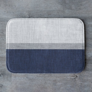 May include: A blue and white striped bath mat with a textured surface.