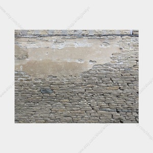 May include: A weathered stone wall with a section of exposed plaster. The wall is constructed of rectangular, gray stones, with a lighter-colored plaster section above. The plaster is chipped and worn, revealing the underlying structure.