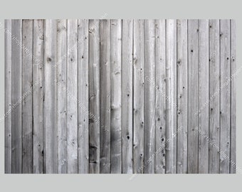 May include: A close-up of a weathered wood fence with vertical planks. The wood is a light gray color with some darker brown knots and grain patterns.