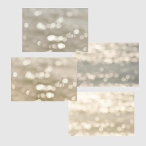 Op de afbeelding: Vier rechthoekige afbeeldingen van wazig water met glinsterende highlights. Het water heeft een lichtbeige kleur, met heldere, onscherpe witte en gele reflecties. Het algehele effect is zacht en dromerig.