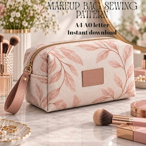 Puede incluir: Un neceser rectangular de tela color crema con un estampado de hojas en rosa suave. La bolsa tiene una cremallera dorada, una correa de muñeca rosa a juego y una etiqueta rectangular vacía en la parte frontal. Texto: MAKEUP BAG SEWING PATTERN A4 A0 letter Instant download.