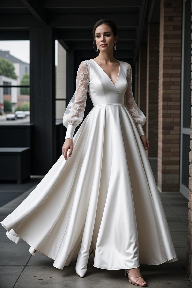 K&ouml;nnte beinhalten: Ein wei&szlig;es Satin-Hochzeitskleid mit V-Ausschnitt und langen &Auml;rmeln. Die &Auml;rmel sind aus durchsichtiger Spitze und haben ein bauschiges Design. Das Kleid hat ein tailliertes Oberteil und einen flie&szlig;enden Rock.