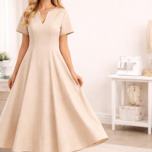 K&ouml;nnte beinhalten: Beiges Midikleid mit V-Ausschnitt und kurzen &Auml;rmeln. Das Kleid hat ein figurbetontes Oberteil und einen ausgestellten Rock. Das Model tr&auml;gt beige Abs&auml;tze. Das Kleid ist f&uuml;r formelle Anl&auml;sse geeignet.
