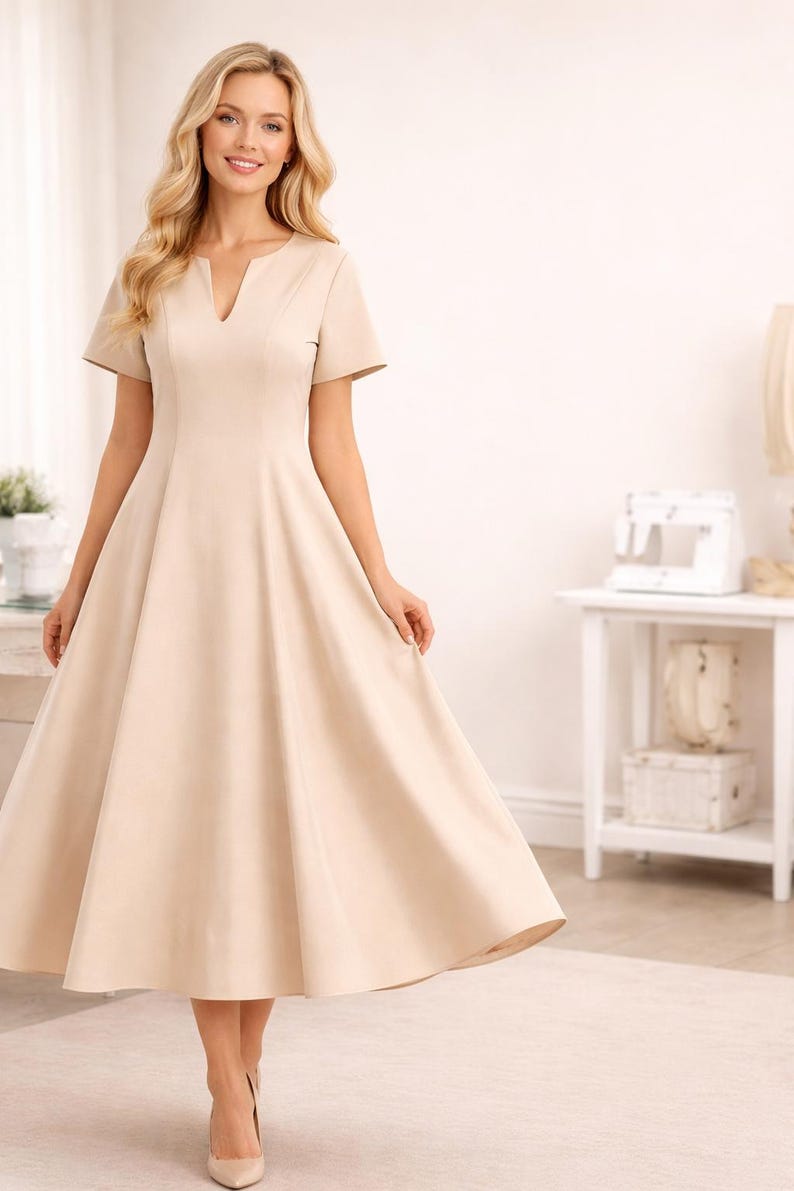 K&ouml;nnte beinhalten: Beiges Midikleid mit V-Ausschnitt und kurzen &Auml;rmeln. Das Kleid hat ein figurbetontes Oberteil und einen ausgestellten Rock. Das Model tr&auml;gt beige Abs&auml;tze. Das Kleid ist f&uuml;r formelle Anl&auml;sse geeignet.