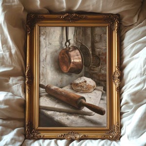 May include: A rectangular gold ornate frame containing a still life print of a copper pot hanging against a brick wall, with a wooden rolling pin and a loaf of bread resting on a stone surface. The frame features intricate carved details.
