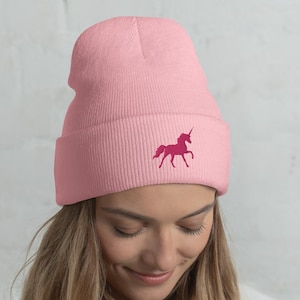 May include: A pink beanie with a pink unicorn embroidered on the front.