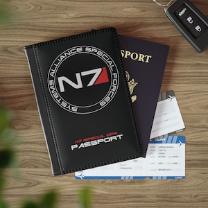 Könnte beinhalten: Ein schwarzer Reisepass-Etui mit dem Text "Systems Alliance Special Forces N7" und "N7 Special Ops Passport".