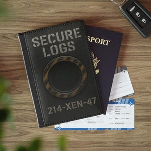 May include: A black leather passport holder with the text "SECURE LOGS" and "214-XEN-47" printed on it. A dark blue passport and two boarding passes are visible. A car key is on the wooden surface.