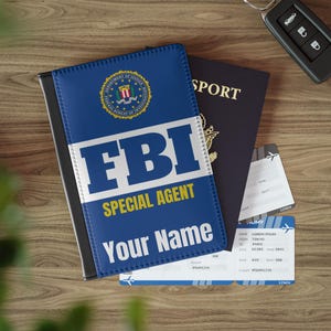 May include: A blue passport holder with the FBI logo and the text "FBI Special Agent" and "Your Name".