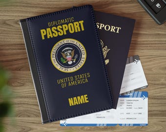 Könnte beinhalten: Ein blauer Reisepass-Etui mit den Worten "DIPLOMATIC PASSPORT" in goldenen Lettern. Das Etui zeigt das Siegel des Präsidenten der Vereinigten Staaten und die Worte "UNITED STATES OF AMERICA". Das Etui trägt auch das Wort "NAME" aufgedruckt.