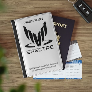 May include: A white passport holder with a black border and the words "PASSPORT" and "SPECTRE" in black text. The holder has a black and white logo with the words "Office of Special Tactics and Reconnaissance".