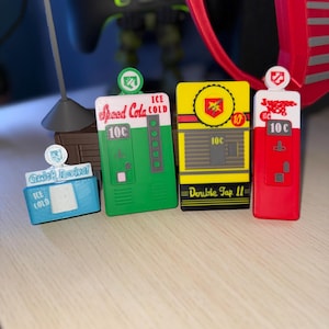 Op de afbeelding: Vier kleurrijke tokens met een gamethema. De tokens zijn blauw, groen, geel en rood, elk met unieke ontwerpen en tekst. De tekst bevat "Quick Revive", "Speed Cola", "Double Tap II" en "Juggernog", met "10c" op elk.