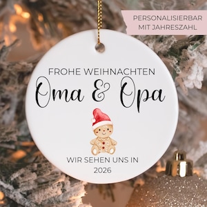 Könnte beinhalten: Weihnachtsornament aus weißer Keramik mit goldener Aufhängeschnur. Das Ornament zeigt den Text "Frohe Weihnachten Oma & Opa" und einen Lebkuchenmann mit Weihnachtsmütze. Das Jahr 2026 ist ebenfalls aufgedruckt.